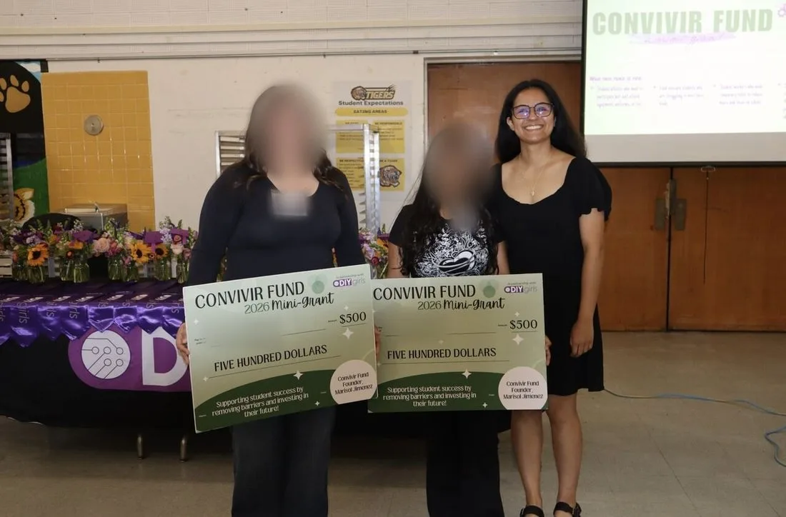 Two grant recipients holding oversized Convivir Fund checks, standing beside Marisol at the award presentation.