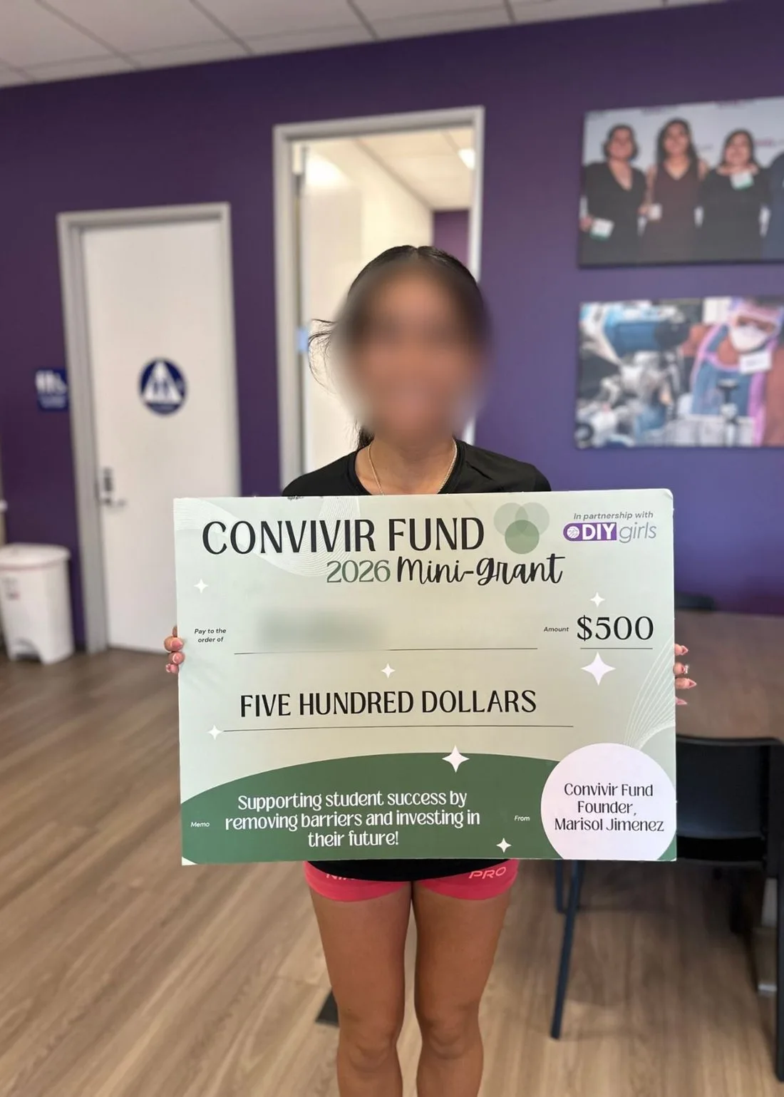A grant recipient holding a Convivir Fund 2026 Mini-Grant check for $500.