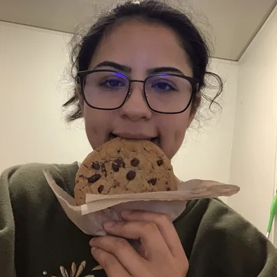 Marisol biting a chocolate chip cookie.