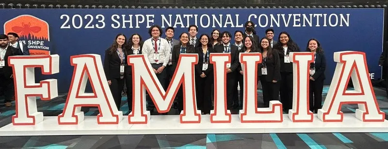 Marisol with a large group at the 2023 SHPE National Convention, standing behind giant FAMILIA letters.