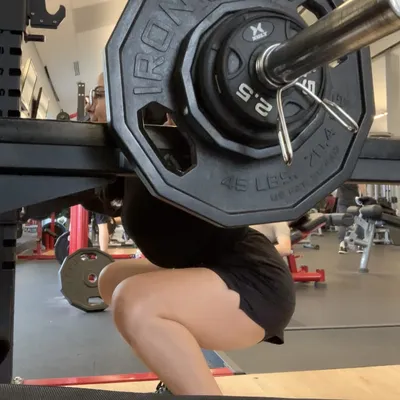 Marisol in a deep squat under a loaded barbell at the gym.