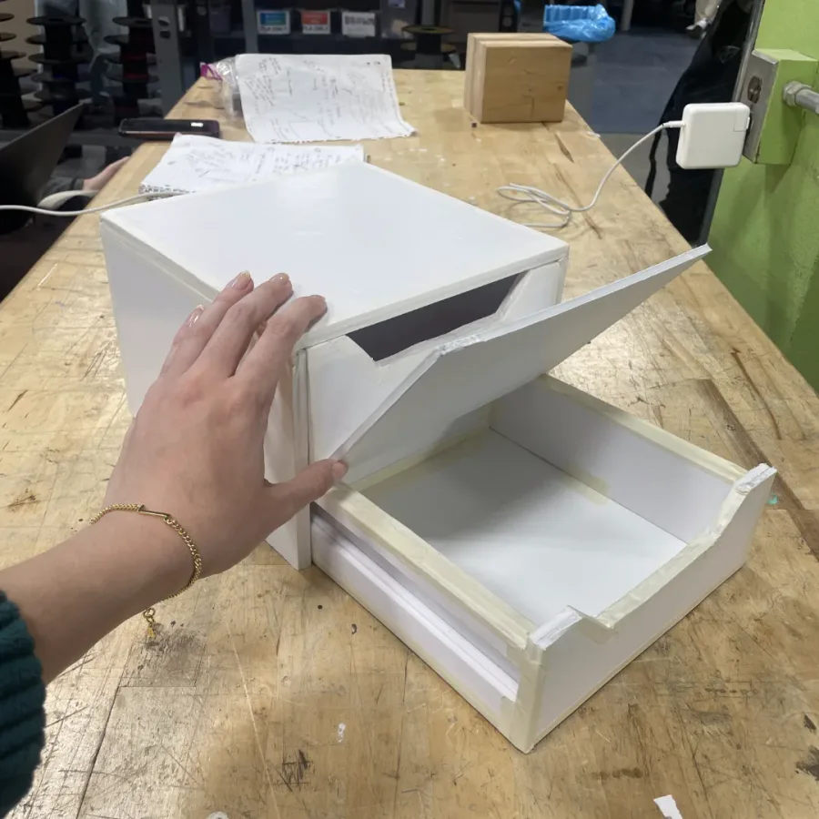 Foam-board prototype with a hand sliding a drawer step out.